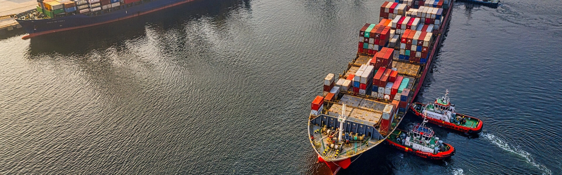 A large cargo ship accompanied by two smaller tugboats